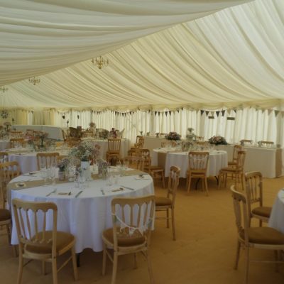 Alternative angle of pretty marquee featuring chandeliers and bunting on chairs.