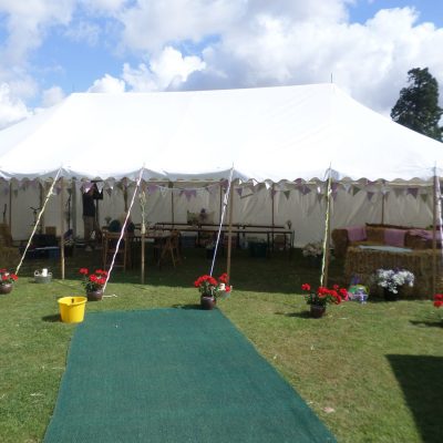 Open marquee with bunting and straw bale seats inside
